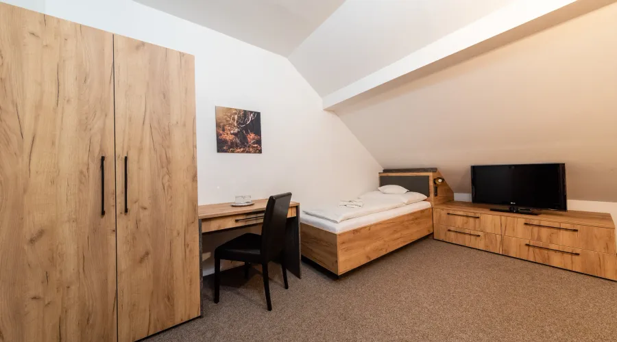 Attic room with a bed and a writing desk