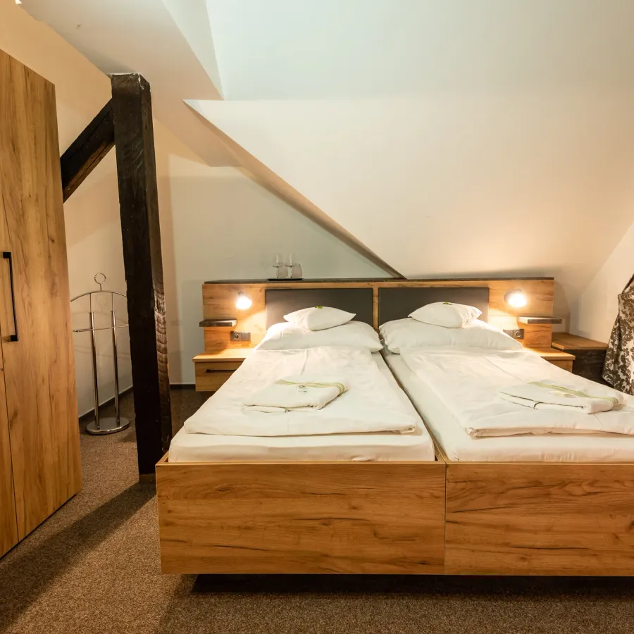 Attic room with exposed beams, a double bed and an extra bed